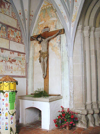 Spätgotischer Kruzifixus, Ende 16. Jh., rechts daneben angeschnitten das romanische Portal